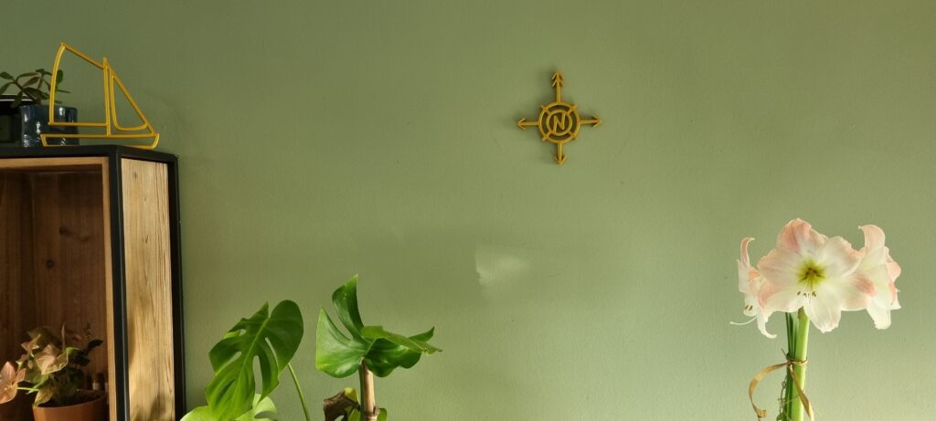 Gouden kompas wanddecoratie 3D-geprint met windstreken aan een muur.